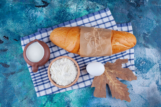 美味面包 面粉 鸡蛋和牛奶放在蓝色的茶巾上面包面团茶毛巾