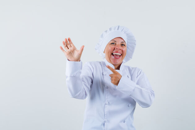 年轻一个穿着白色制服的女厨师摆出一副很高兴的样子 像是指着手里的东西时尚厨师指向