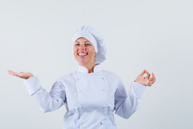 魅力一位身穿白色制服的女厨师 一边摊开手掌 一边摆出ok的姿势 看上去很乐观制服年轻粉色