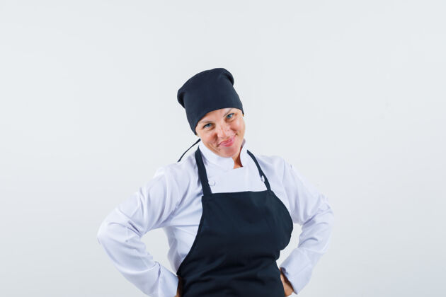 长相一个金发女人 手放在腰上 穿着黑色的厨师制服摆在前面 看起来很漂亮模特脸皮肤