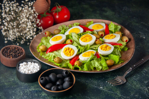 盘子鸡蛋沙拉由橄榄和蔬菜沙拉组成 背景为深蓝色沙拉景观前面