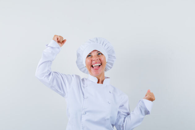 魅力身着白色制服的女厨师展示着赢家的姿态 看上去很幸福厨师显示喜悦