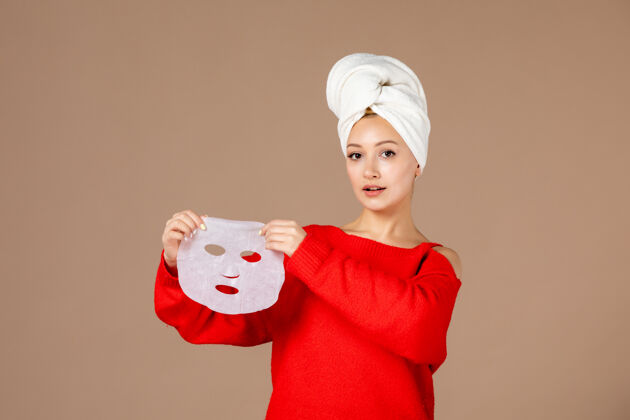 女人正面图粉色背景上手拿面罩的年轻女性面霜面具头发