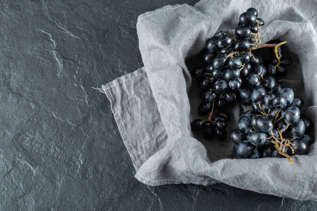 紫色在灰色桌布上的篮子里放着新鲜的黑葡萄黑色顶视图美味