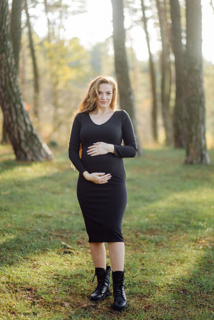 树在森林里散步的怀孕的快乐的年轻女人期待腹部白种人