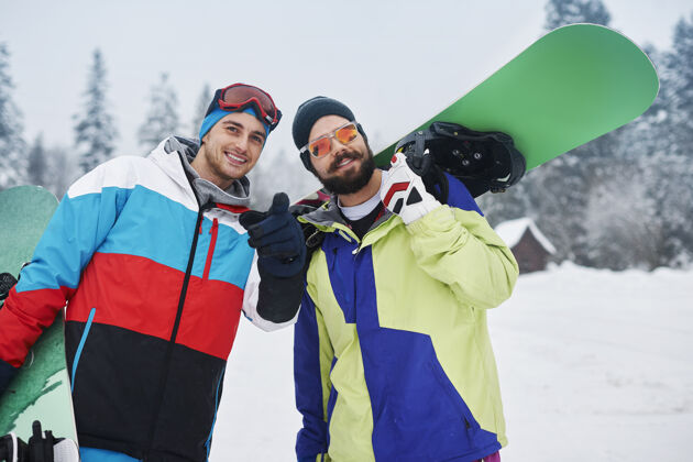 倾斜两个家伙在寒假玩滑雪板滑雪板冒险看向别处