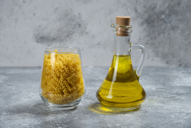 未经料理的一个装有生螺旋通心粉和一瓶油的玻璃碗美味通心粉可食用的