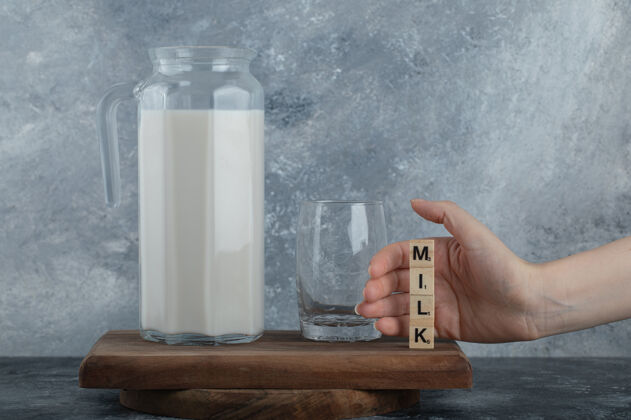 罐子女人的手拿着木头字母和鲜奶产品字母乳制品