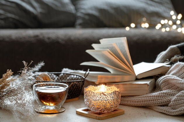 蜡烛静物与一杯茶 书籍和燃烧的蜡烛在一个美丽的烛台家居舒适的概念构图玻璃杯子