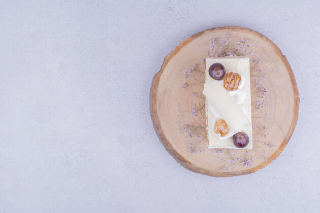 美味在木板上放一片椰子蛋糕 上面有葡萄和核桃奶油甜点美味
