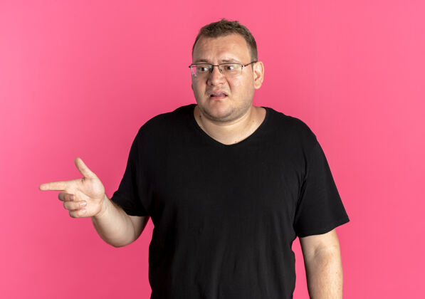 目录戴眼镜的超重男子身穿黑色t恤 看上去很困惑 用食指指着粉色的一边T恤看黑色