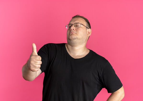 T恤戴眼镜的超重男子身穿黑色t恤 看上去自信满满 竖起大拇指 而不是粉色男人自信穿