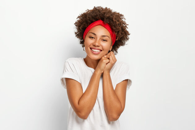 脸迷人的非洲发型年轻女子 双手紧握 戴着红色头带 穿着休闲服耳环衣服单色