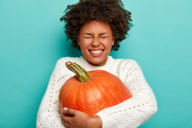 室内感恩节和秋天的时间概念快乐的黑皮肤女人拥抱秋收 大橘子南瓜年轻人庆祝收获