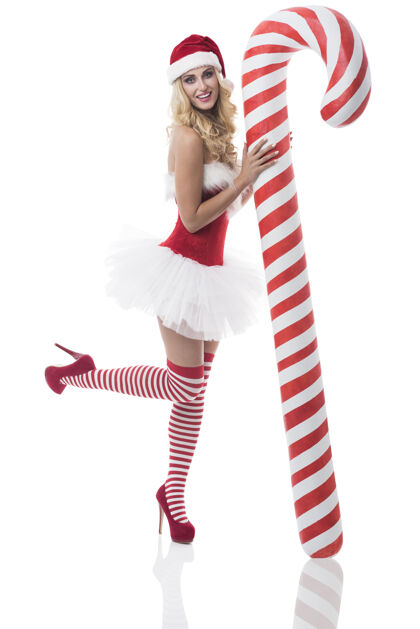 女人穿着圣诞老人服装的性感女人在白墙上摆姿势袜子瘦高跟鞋