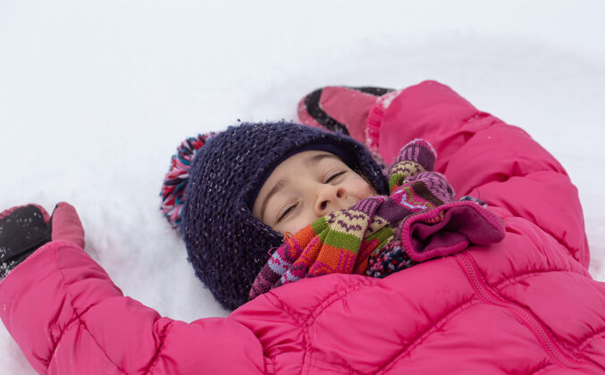 乐趣一个穿着粉色夹克的小女孩在刚刚下过的雪上做了一个天使童年冬天天使