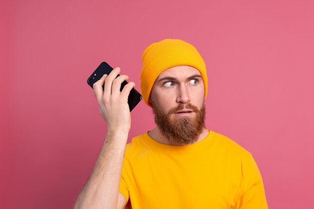 记录年轻的欧洲帅哥笑容可掬地用粉色智能手机听音频留言模型胡须技术