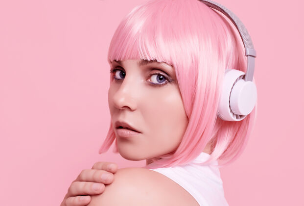 美丽粉红头发的美女肖像在耳机里欣赏音乐微笑耳机女人