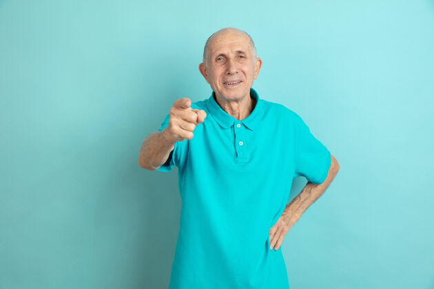 健康指着 选择你蓝色工作室里的高加索老人肖像工作模特健康