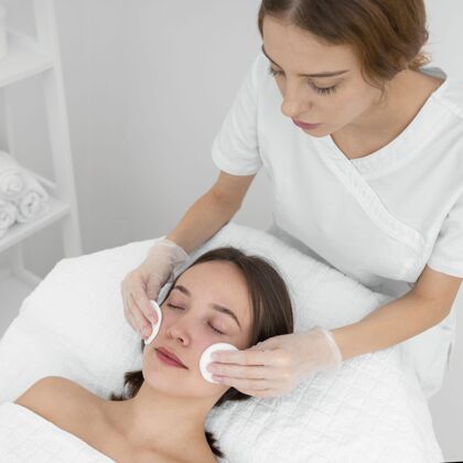 美容护理美容院的女性客户 用清洁盘进行面部护理美容院治疗女人