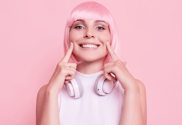 微笑粉红头发的美女肖像在耳机里欣赏音乐放松快乐成人