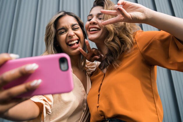 分享两位年轻朋友在户外玩得开心 用手机自拍的照片手机休闲电话