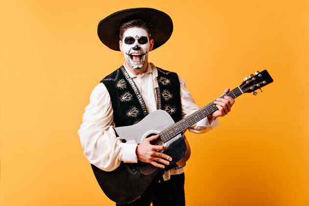 墨西哥积极的人在睡衣里唱小夜曲积极的人手里拿着吉他在黄色的墙上摆姿势吉他音乐家室内
