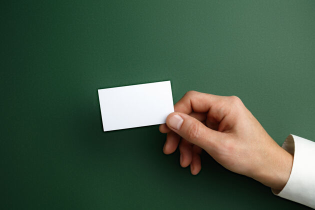 手臂男性手拿一张空白名片放在绿色的墙上 用于文字或设计空白信用卡模板用于联系或在商业 金融 办公室使用复制空间问候语工人商务人员