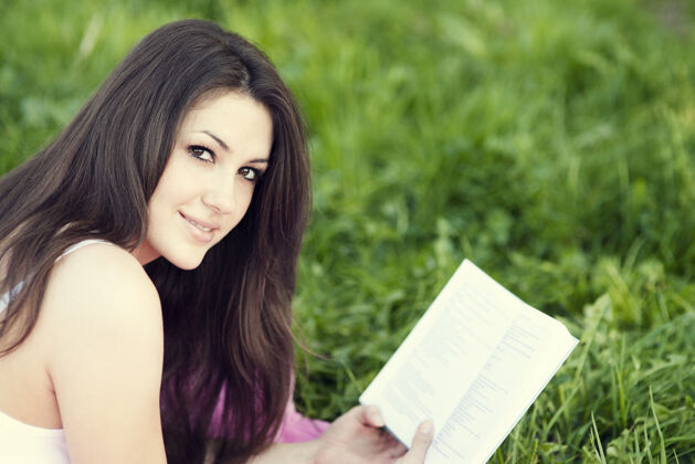 阅读在草地上看书的年轻女人快乐时尚看