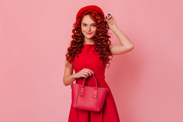 发型粉红色空间里 一个卷曲的蓝眼睛女人的肖像一个穿着鲜红衣服的女人摆姿势 微笑着看着相机女士浪漫女性