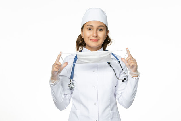 医疗正面图女医生身穿白色医疗服手持口罩在白墙上大流行疾病药物病毒隔离听诊器制服女性