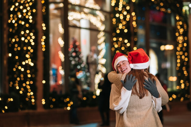 灯光在圣诞夜户外散步时 快乐可爱的年轻朋友们互相拥抱微笑的照片节日女人快乐