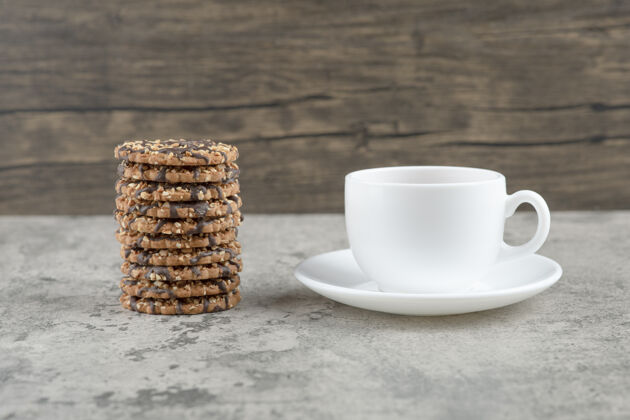 烘焙燕麦片饼干加巧克力糖浆和一杯茶放在石桌上茶杯子饼干