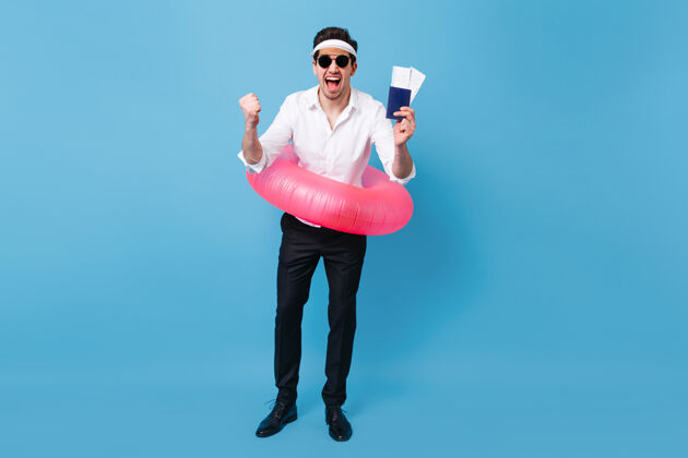 优雅一个穿着西装 戴着太阳镜 手里拿着文件 机票和粉色充气圈的男人享受假期旅行的全长片老板帽子黑发