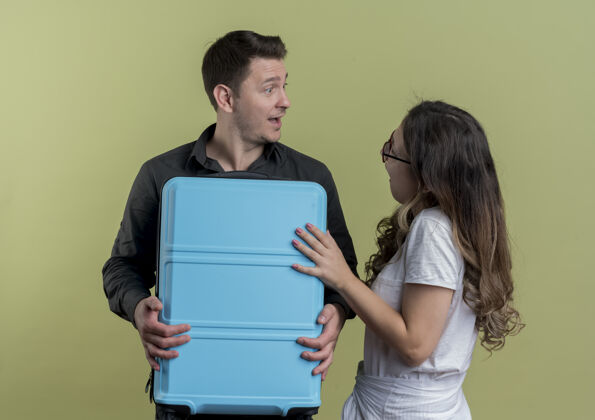 夫妇一对幸福的年轻游客 一男一女拿着手提箱 站在轻薄的墙上 神情惊讶站着手提箱抱着