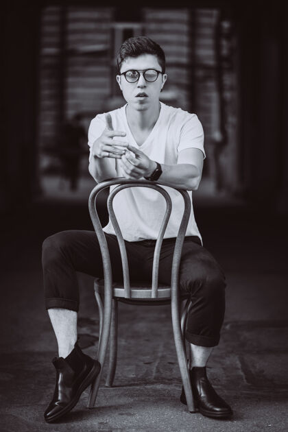 黑街上穿着白色t恤 戴着墨镜坐在椅子上的男人的画像男孩眼镜男