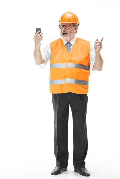 保护一个穿着建筑背心 戴着橙色头盔的建筑工人在用手机谈论着什么工人黄色人员