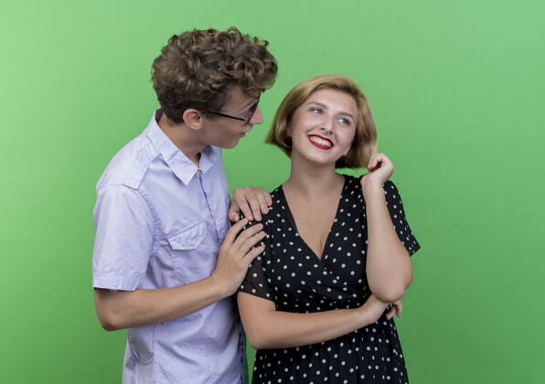 情侣年轻漂亮的夫妇惊讶地看着他心爱的女朋友站在绿色的墙上微笑着看站年轻