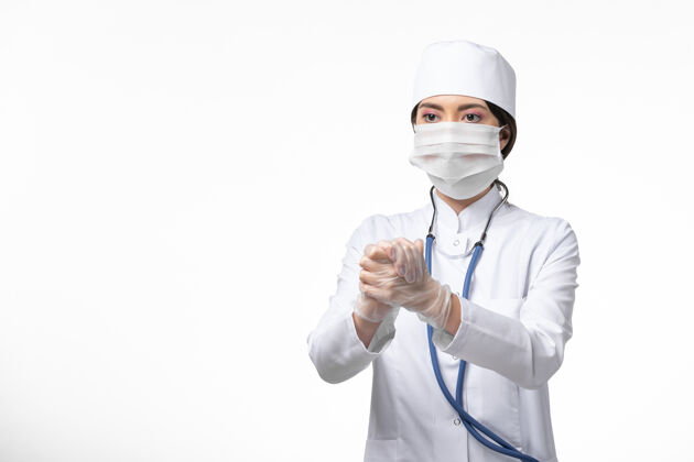 视图正面图女医生穿着白色无菌医疗服 带着口罩因柯维德-白墙病握手-柯维德-大流行病毒病女性正面面罩