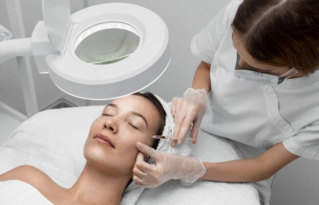 女人美容师在给女性客户注射填充物美容院美容治疗填充物