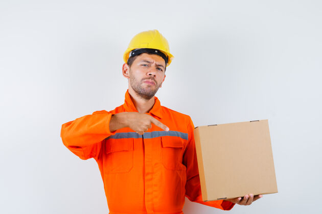 防护建筑工人穿着制服指着纸板箱 头盔正视图起重机设备头盔