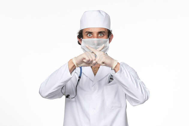 视图正面图：男医生穿着医疗服 戴着口罩 以防白色桌面病毒溅起冠状病毒大流行人冠状病毒人