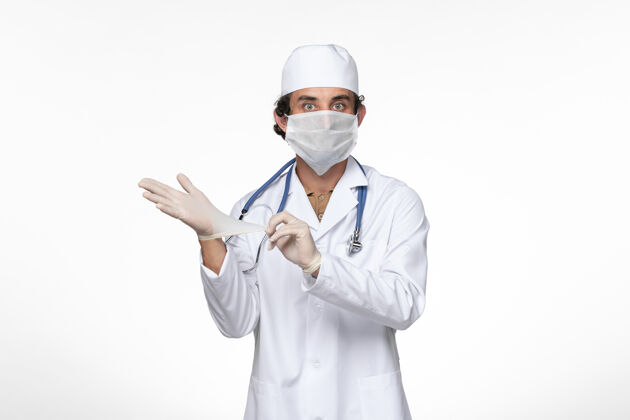 实验室外套正面图：男医生穿着医疗服 戴着无菌口罩作为防护罩 戴着白桌子上的手套 病毒疾病 病毒大流行疾病外套冠状病毒医疗