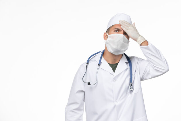 专业正面图男医生穿着防毒服 戴着防冠状病毒口罩 在白墙上检查体温冠状病毒病隔离大流行对抗医疗男性