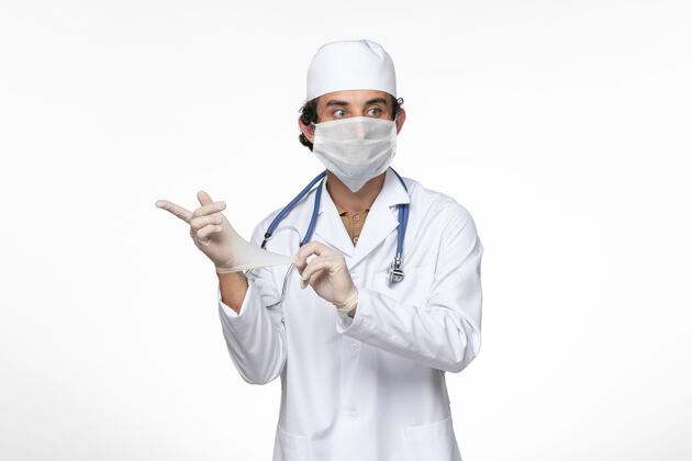 实验室外套正面图男医生穿着医疗服戴着无菌口罩作为防护罩-戴着手套上白墙病毒病-病毒大流行病手套穿戴面罩