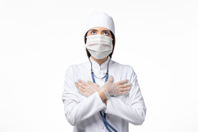 医疗正面图女医生身穿白色无菌医疗服 带口罩 因冠状病毒在祈祷姿势上白墙病大流行病毒冠状病毒医生病毒消毒
