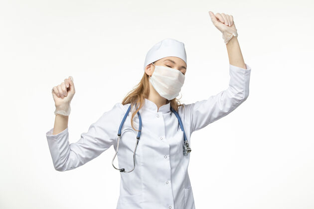 人员正面图女医生穿着医疗服带着无菌口罩因冠状病毒在白墙上起舞疾病大流行健康冠状病毒视野医生舞蹈