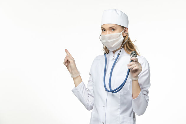 大流行前视图穿着白色医疗服的女医生在白色办公桌上使用听诊器疾病冠状病毒-大流行疾病专业人员视图医疗