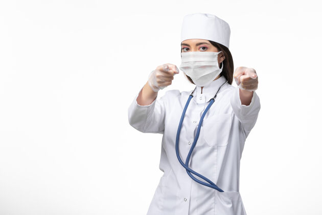 外套正面图女医生穿着白色医疗服 戴着口罩 由于白色办公桌上有冠状病毒 健康疾病大流行covid-面罩医务人员套装