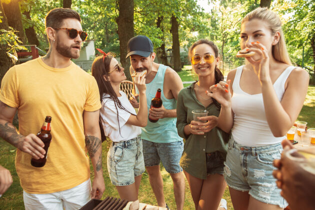 啤酒一群快乐的朋友在阳光明媚的日子里喝着啤酒 一起烧烤一起在户外的林间空地或后院休息喝吃自然